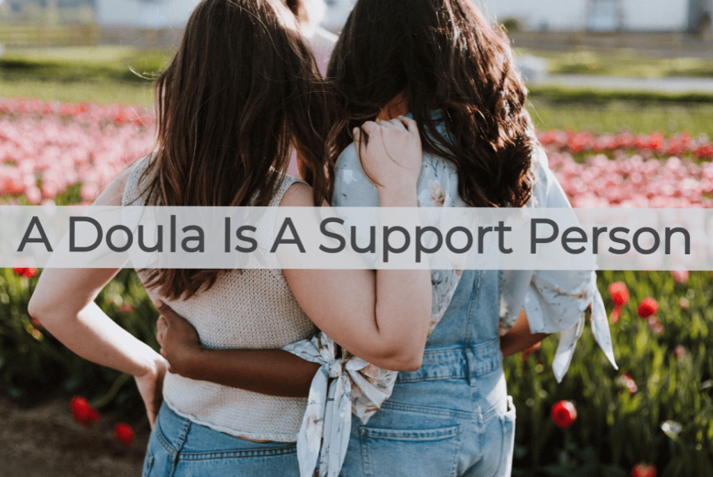 Doulas supporting each other outside in a bed of flowers