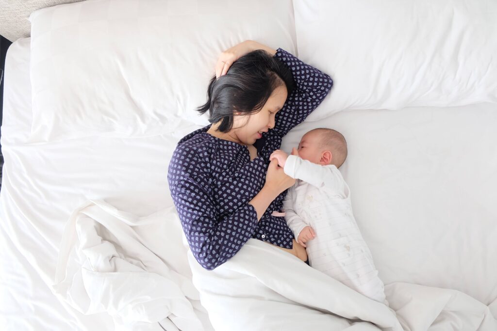 New Mom laying with new born baby in bed