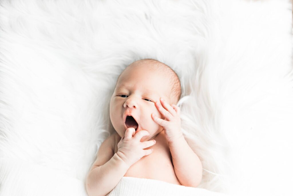 Newborn Baby yawning while laying in bed